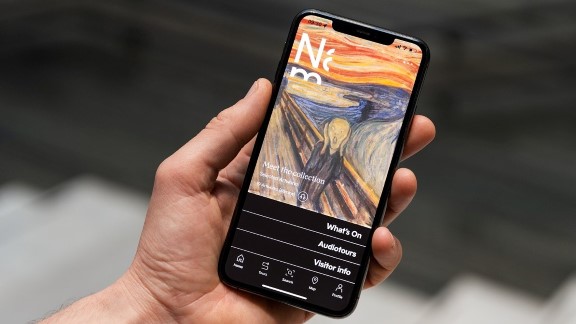 Hand holding smartphone with a museum app on the screen