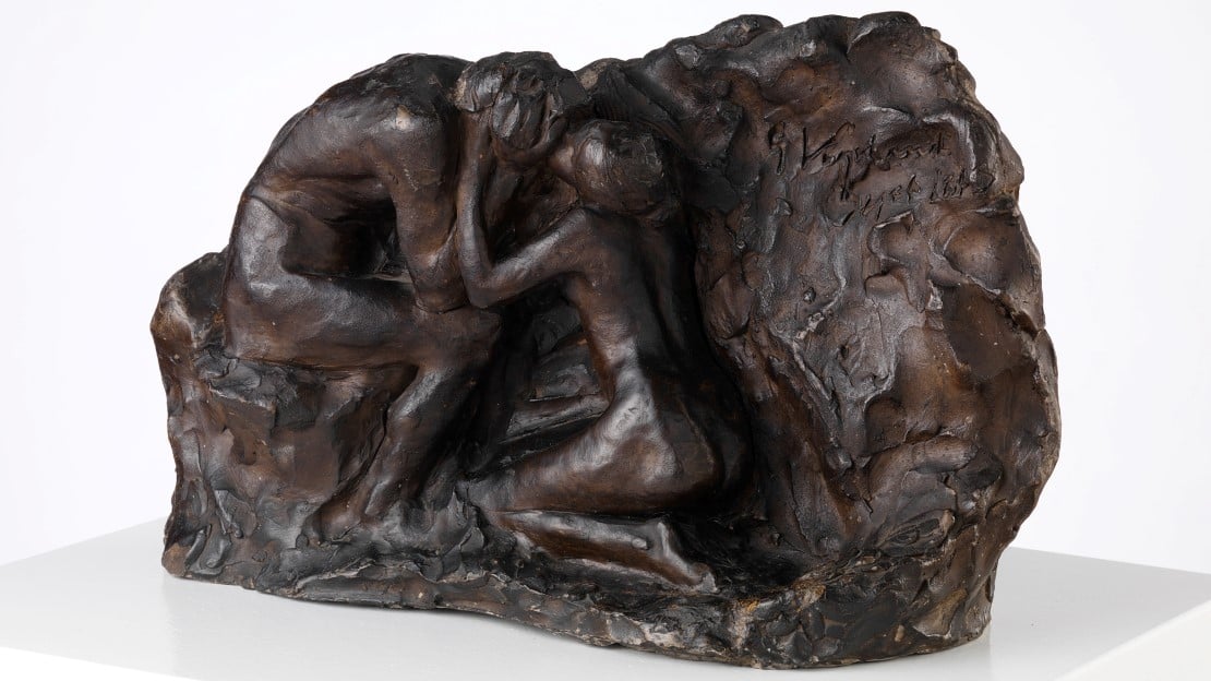 Steinskulptur av to mennesker. Det ene trøster det andre.