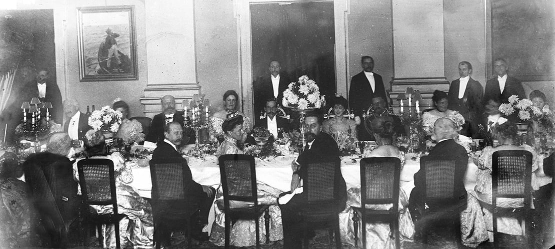 a lot of dressed up people around a dinner table