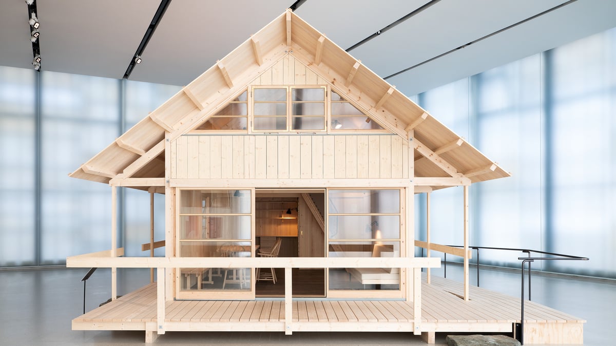 En trehytte inne i en stor og lys museumshall