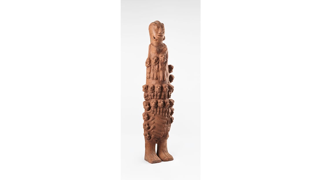 En totemformet figur bestående av mindre menneskelignende figurer. Utformet i terrakotta.