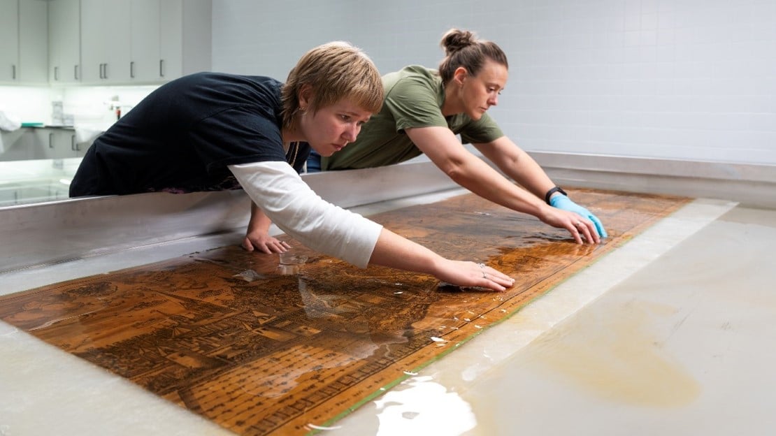 Papirkunst kan variere veldig i størrelse og utrykk. Her vasker to av museets konservatorer et stort litografi.