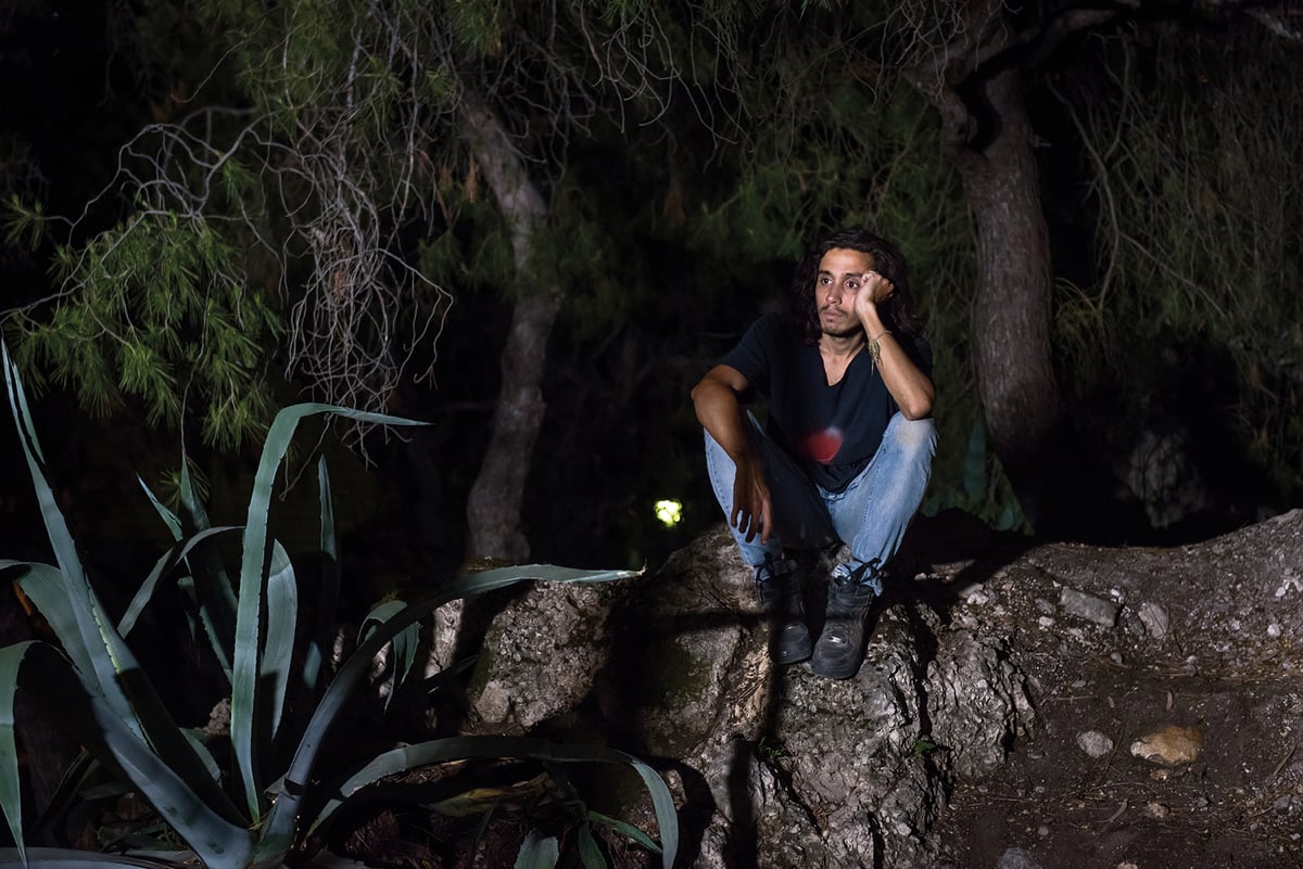 Fotografier viser kunstneren Adrian Villar Rojas som sitter ute i naturen med trær rundt, om natten.
