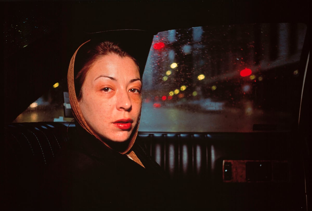 Nan Goldin, «Kathleen in the Taxi to Greer's Funeral. Chicago», 1996 En kvinne sitter inne i en taxi og ser direkte på fotografen
