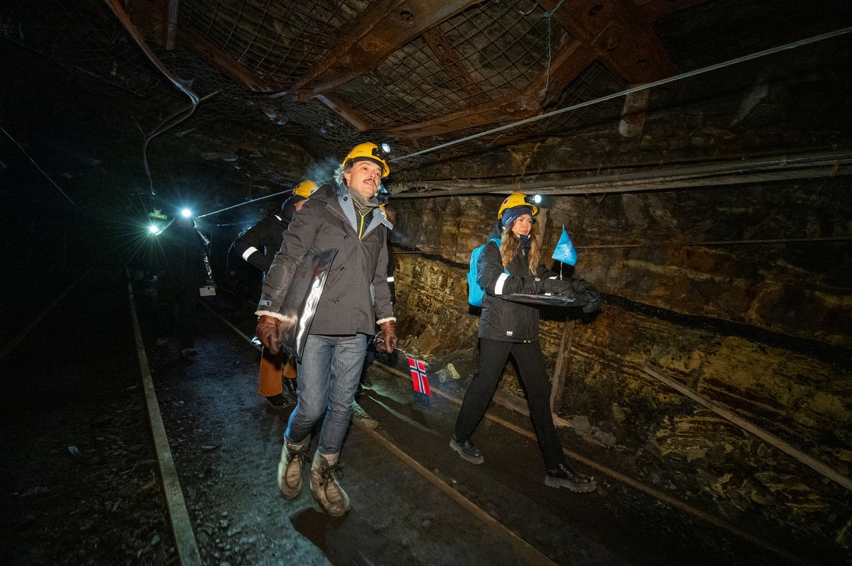 Mennesker på vei ned i gammel gruve over skinnegang