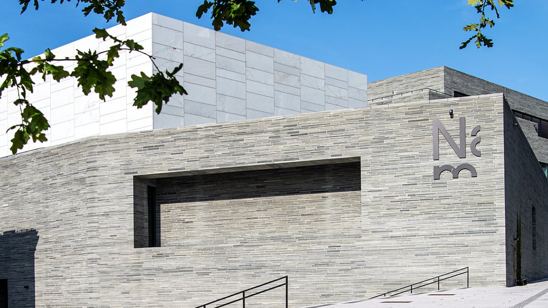 A building in marble and grey stone. Modern architecture.  Blue sky wit some clouds.