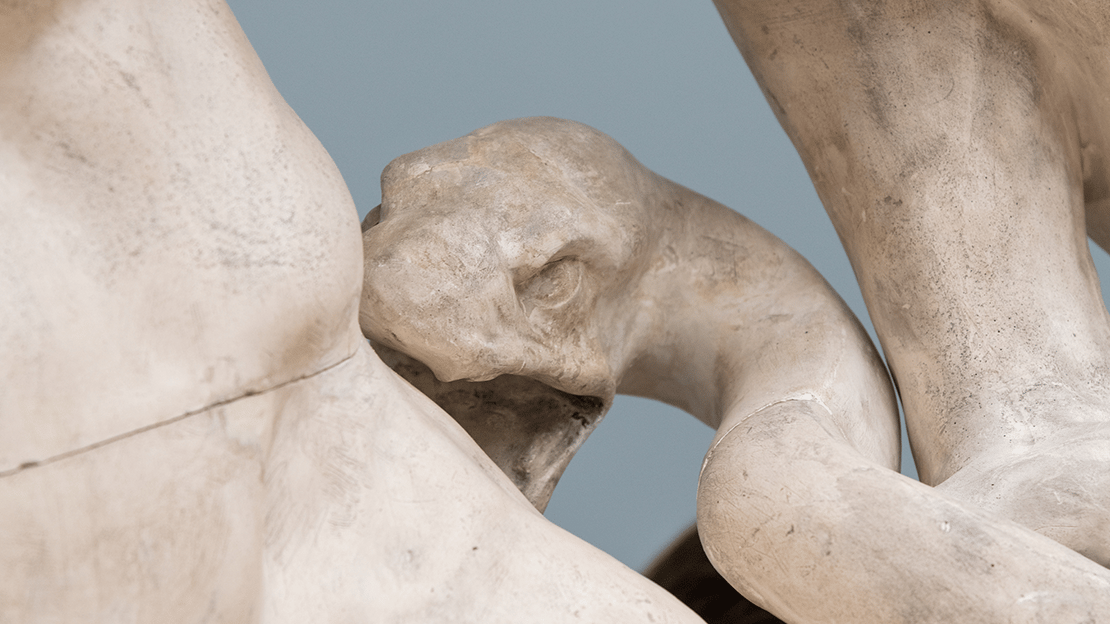 Bildet viser en skulptur av en slange som biter et menneske