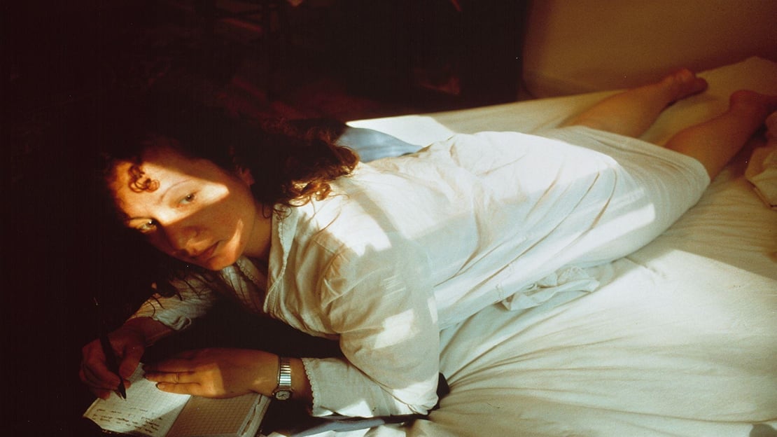 Nan Goldin, Self-Portrait Writing in Diary, Boston, 1989 En kvinne ligger på en seng. Hun skriver i en bok.
