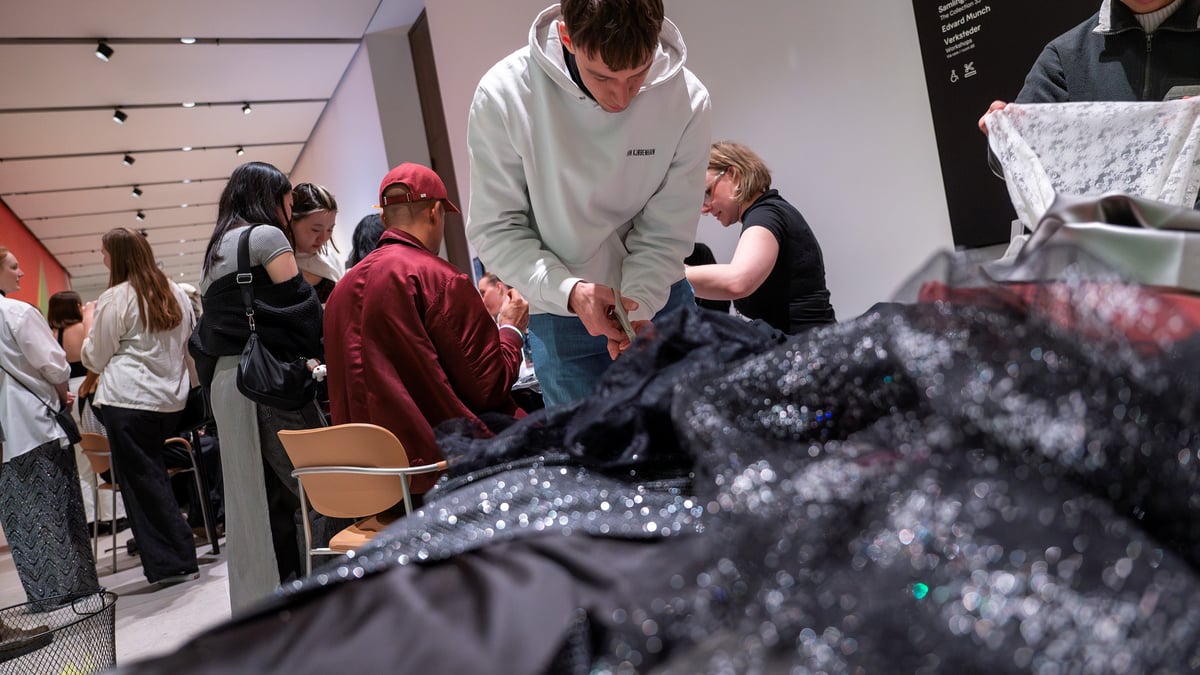 Ung man arbeider forover lent med et stort stykke sort tekstil som glitrer