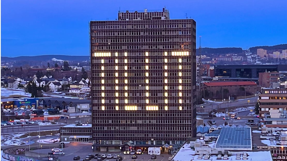 En fraflyttet 20-etasjers høyblokk på Økern i Oslo, hvor vinduer over 9 etasjer lyser opp og former ordet tillit på begge sider.