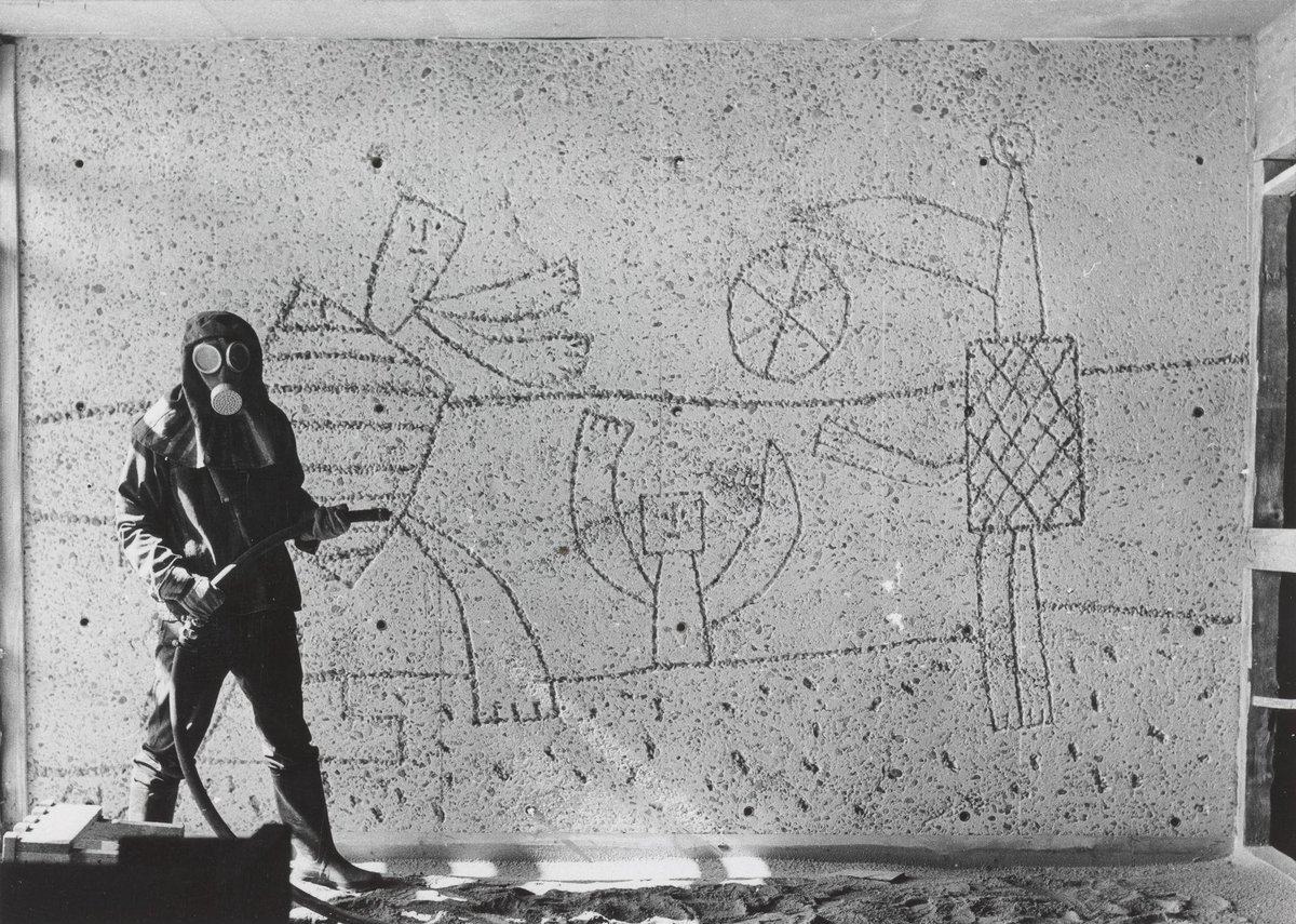 Carl Nesjar sandblåser Picassos motiver i Høyblokka, antagelig i 1959. Mann i drakt som sandblåser motiver i betongvegg
