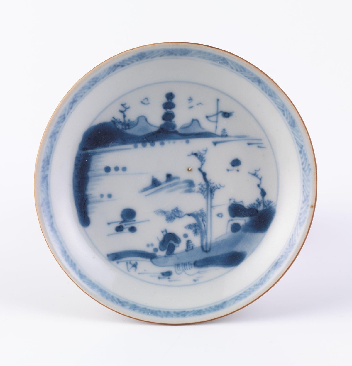 Hvit tallerken med blå dekor av landskap