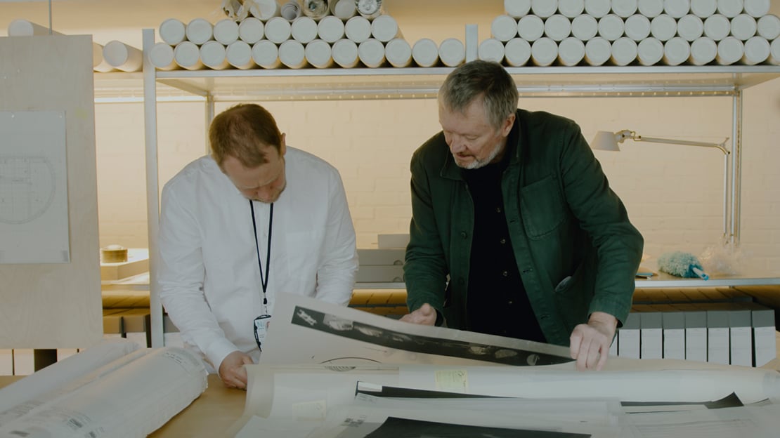 F.v. Joakim Skajaa, kurator i Nasjonalmuseet og Kjetil Trædal Thorsen, grunnlegger og arkitekt i Snøhetta. To menn står bøyd over arkitektplansjer.