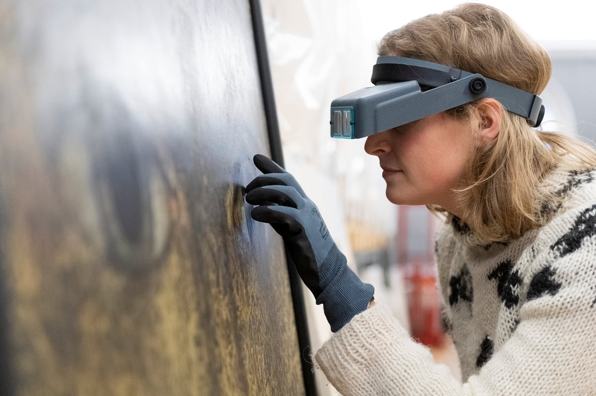 kvinne med forstørrelsesbriller undersøker maleri