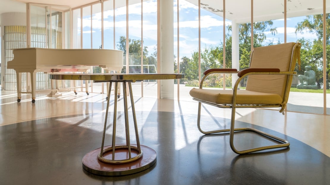 Villa Stenersen En stol, et rundt bord og et flygel i en funkisvilla med store vinduer