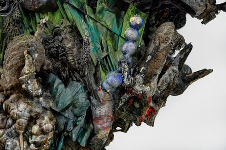 Adrián Villar Rojas. «The End of Imagination I» (detalj), 2022 Bilde viser detalj av en installasjon. Organiske og geometriske former, i ulike materialer, i fargene grønn, blå, grå og brun.