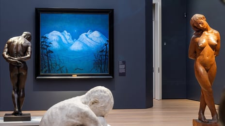 Fotografiet viser tre skulpturer foran et maleri som viser et vinterlandskap med fjell og en stjerne i midten.