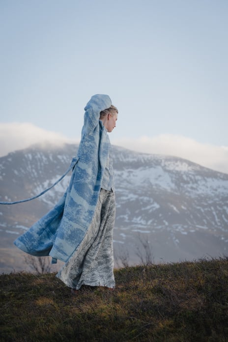 Ramona Salo Myrseth, «Den Samiske Halvtimen», 2024. En kvinne går på fjellet et antrekk med farger og mønster som ligner på fjellet.