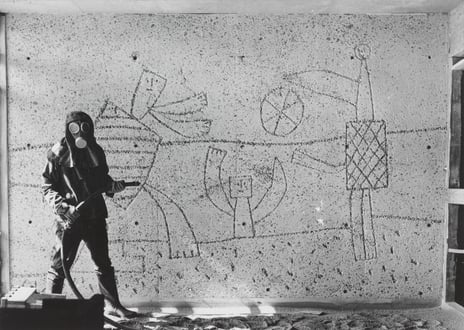 Carl Nesjar sandblåser Picassos motiver i Høyblokka, antagelig i 1959. Mann i drakt som sandblåser motiver i betongvegg