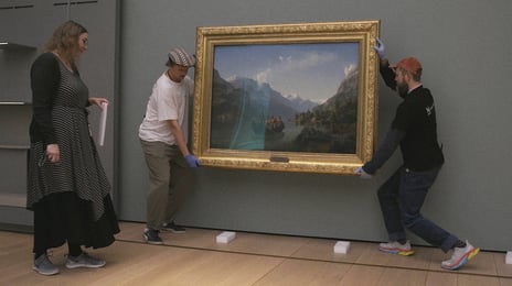 Registrar og magasinteknikere flytter et av museets mest kjente bilder. Kvinne og to menn henger opp ikonisk maleri