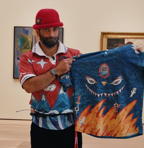 Herr Kunstmaler viser fram sin slemme landslagsdrakt i Nasjonalmuseet. Mann med rød fotballdrakt og hatt viser fram blå fotballdrakt