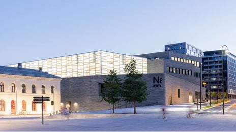 Nasjonalmuseet for kunst, arkitektur og design Nasjonalmuseet sett fra utsiden, med lyshallen opplyst og to trær i forkant