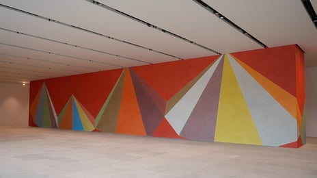 Sol LeWitt, «Wall Drawing #839», 1998/2021 Et stort maleri som dekker gulv til tak på en hel vegg med fargerike triangler