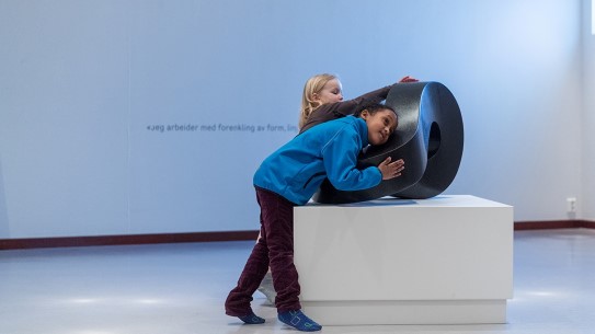 Barn kjenner på en skulptur laget av Aase Texmon Rygh. Barn kjenner på en sort steinskulptur laget av kunstner Aase Texmon Rygh.