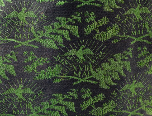 Nærbilete av ein tilsvarande vest som Nordenfjeldske Kunstindustrimuseum eig. Nærbilete av ein vest med grønt mønster på blå bakgrunn.