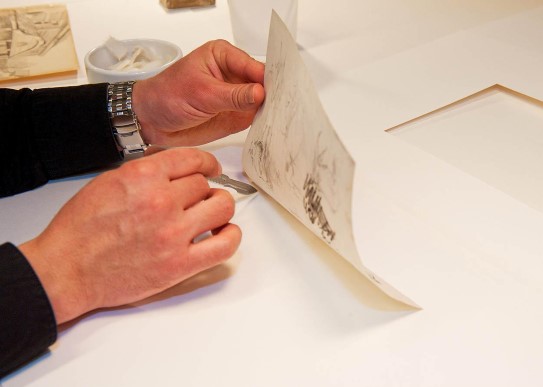 A piece of art is loosened from its assemblage to be conserved.