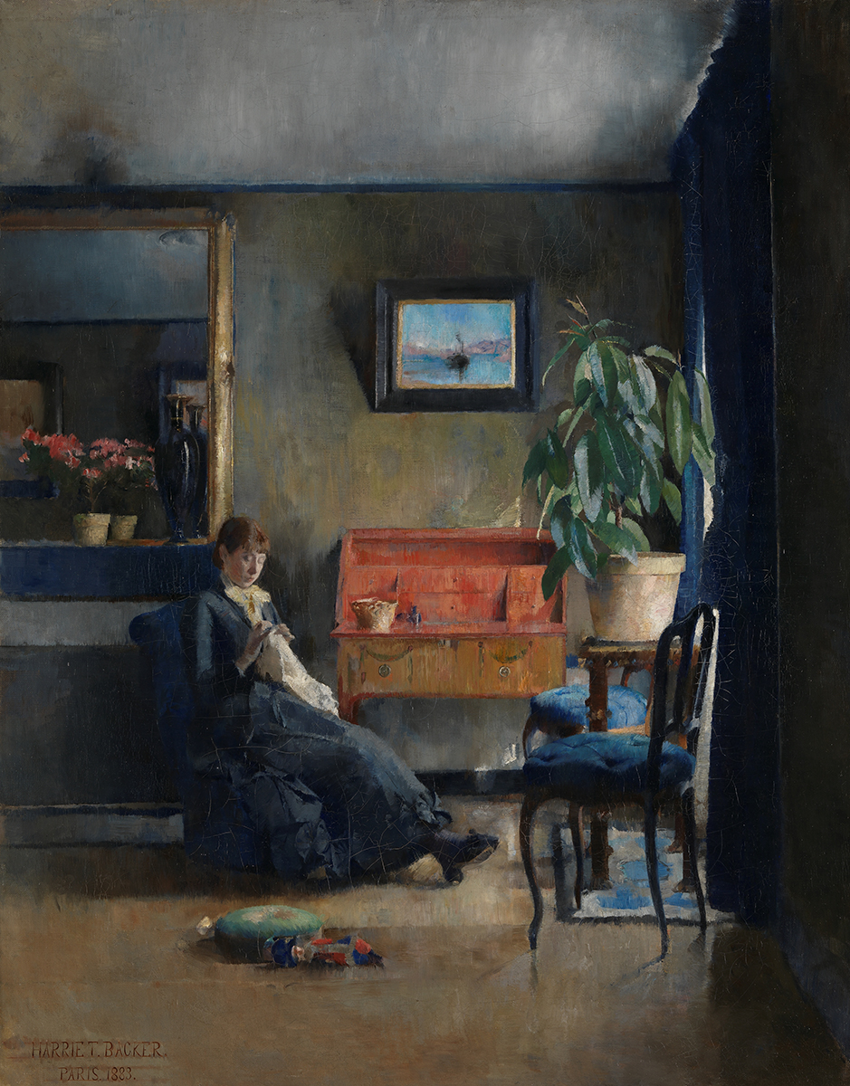 Kvinne sitter med sysaker i stue med blått interiør og en plante og en rød kommode.