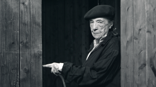 Bilde av Louise Bourgeois i 1992 Sorthvitt portrettfoto av kunstneren Louise Bourgeois som står i en døråpning, ikledd svarte klær