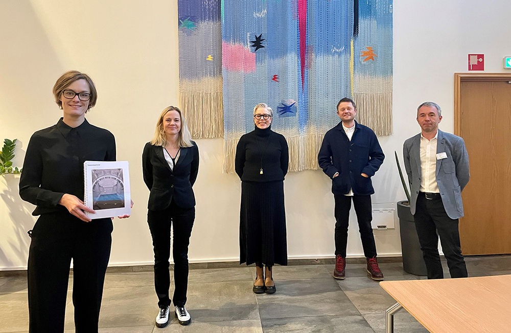 Kulturminister med rapport i hånden. Fem mennesker på rad.