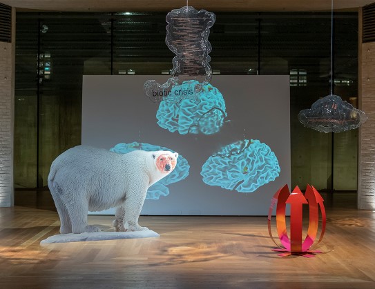 Katja Novitskova, «Pattern of Activation (biotic crisis)», 2017 Isbjørn, røde piler som en busk, hengende store gjennomsiktige "skyer" fra taket. i bakgrunnen en skjerm med tre blå skikkelser