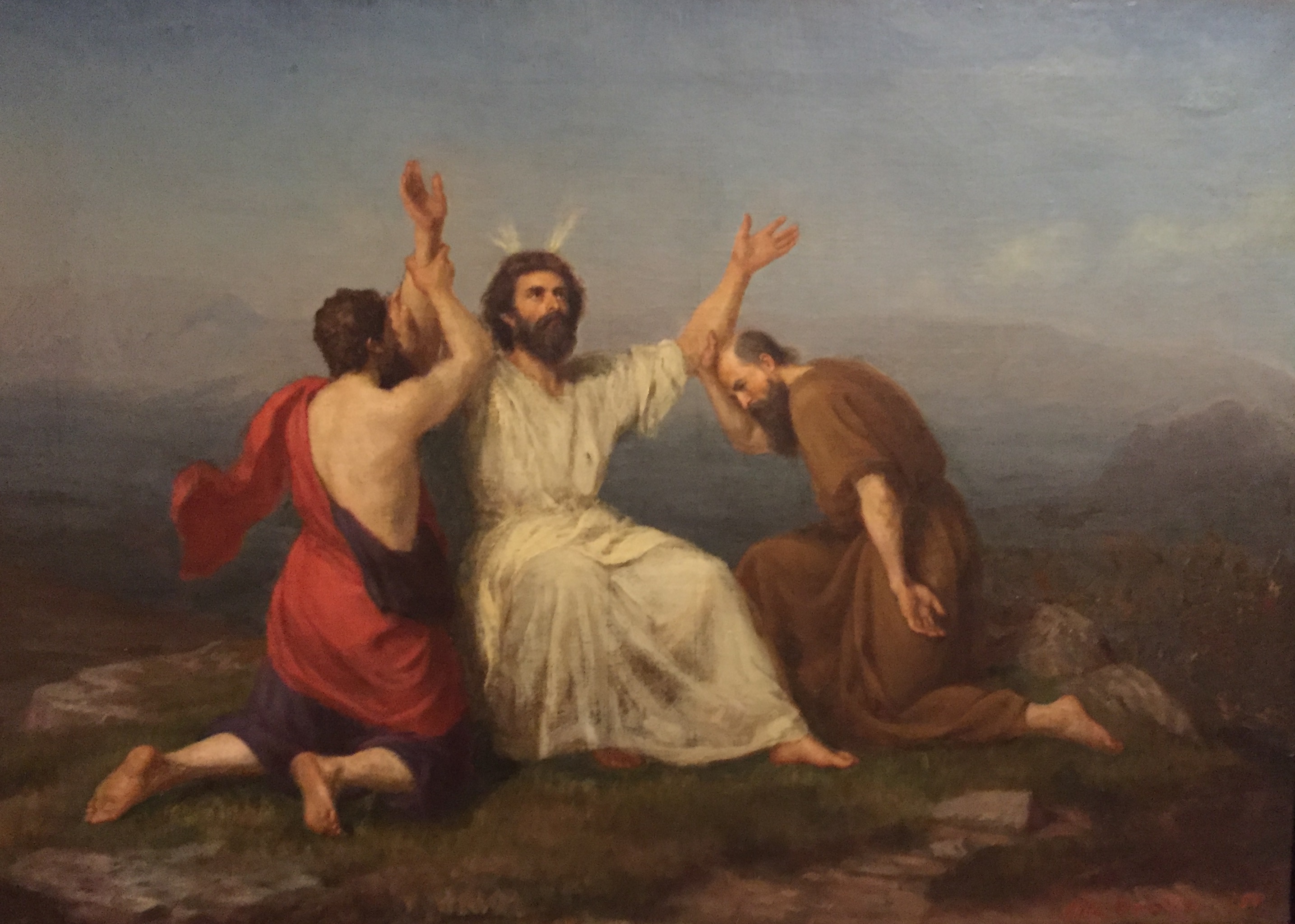 Two men supporting the third, with his hands raised towards the sky