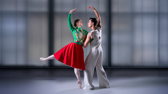 Fotografi av to dansere i Lyshallen i Nasjonalmuseet. Kvinnen er kledd i fargerike klær, mannen er kledd i hvitt.