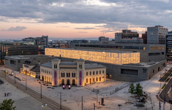 Eksteriør foto av museumsbygg med stor rektangulær hall på toppen med lysglødende vegger