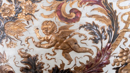 Fotoet viser et nærbilde av mønsteret i et tapet av lær, med en englefigur i midten av gull