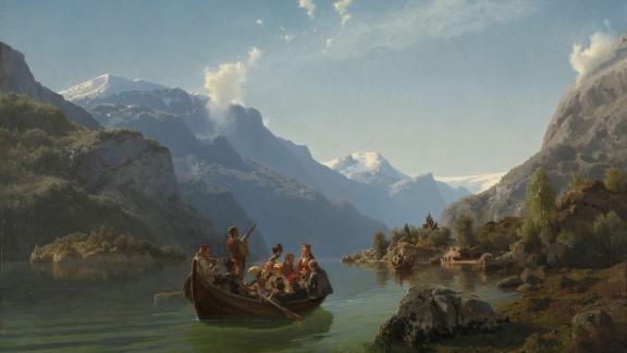 A rowboat with finely dressed people cross a fjord with mountains and a church in the background