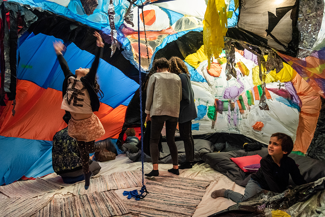 barn og voksne inne i et telt av farger og tekstiler