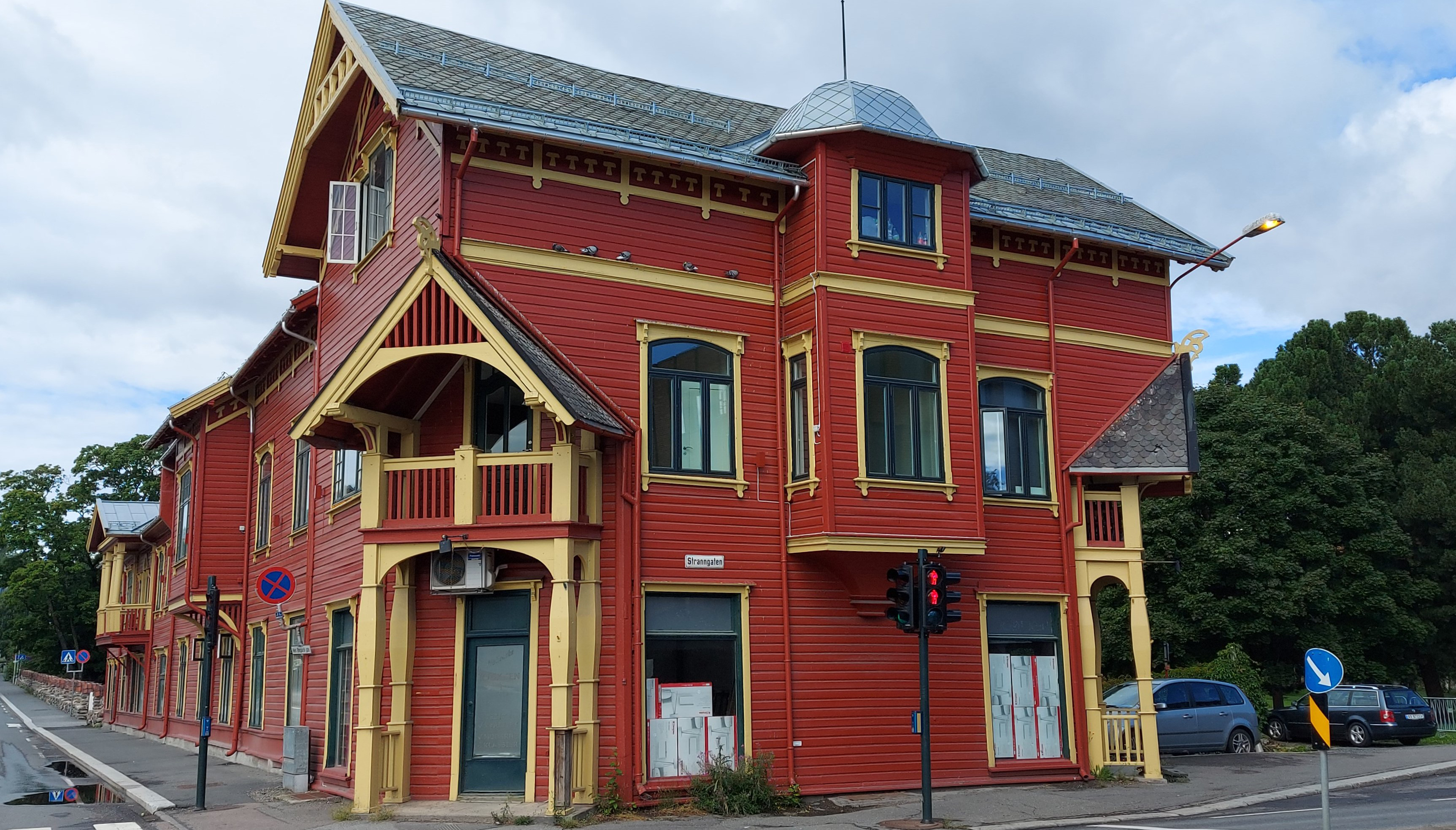 Fotografi av en rød bygning med gule vinduskarmer og detaljer