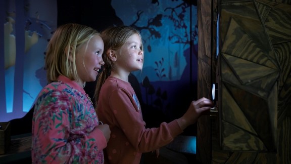 To jenter interagerer med en skjerm i et mørkt rom 
