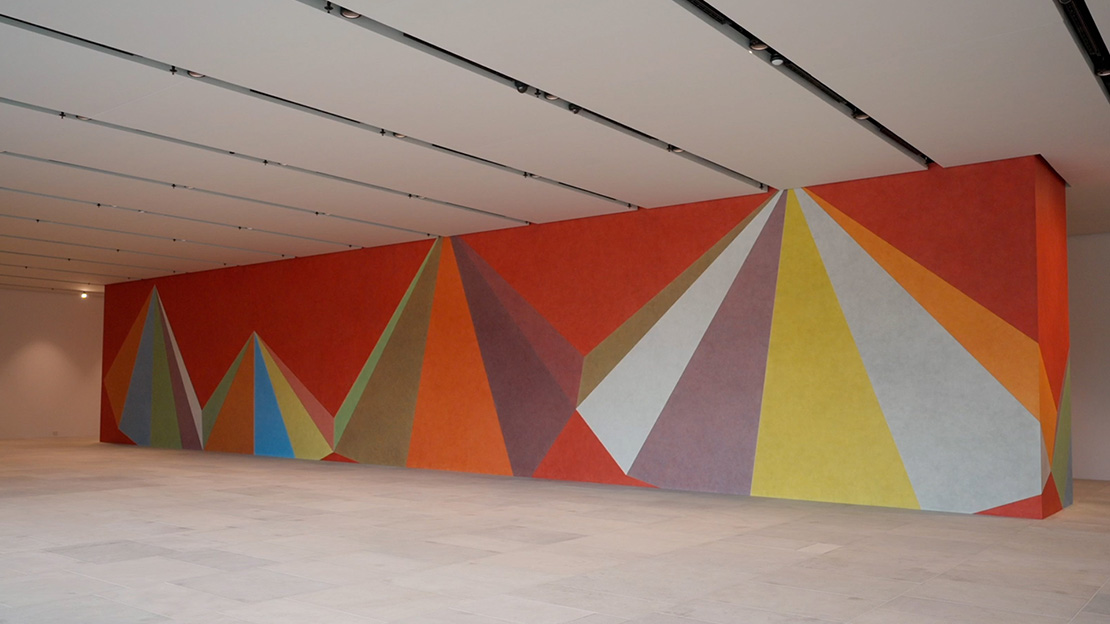 Et stort maleri som dekker gulv til tak på en hel vegg med fargerike triangler