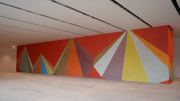 Et stort maleri som dekker gulv til tak på en hel vegg med fargerike triangler